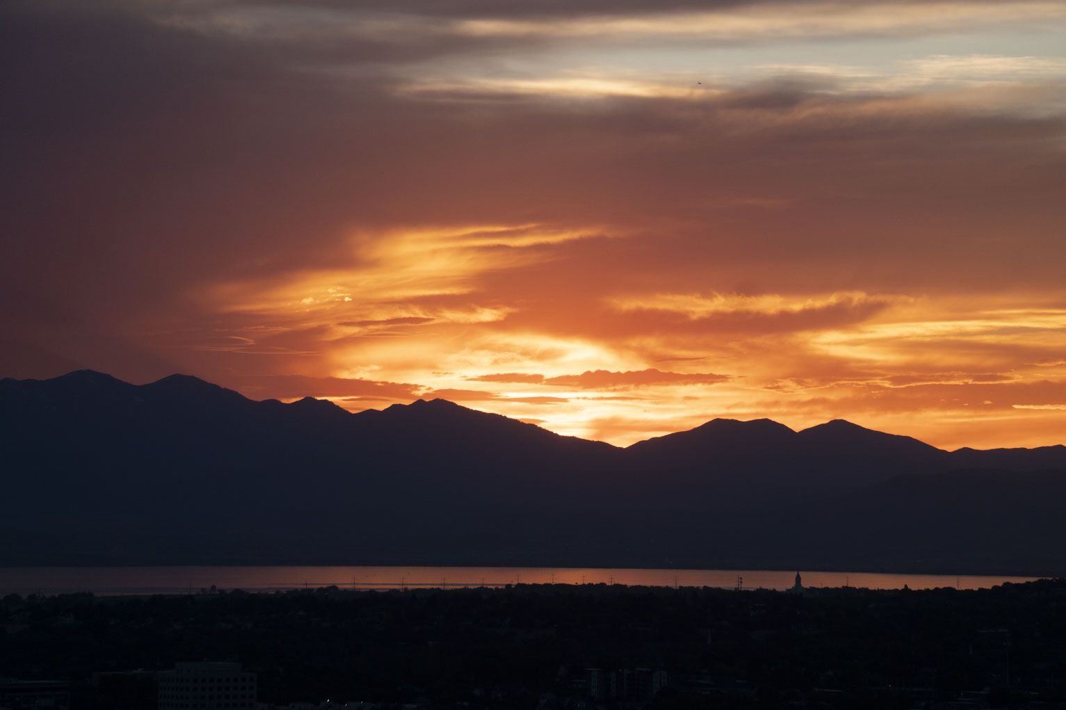 Orange sunset silhouettes the mountains an almost purple